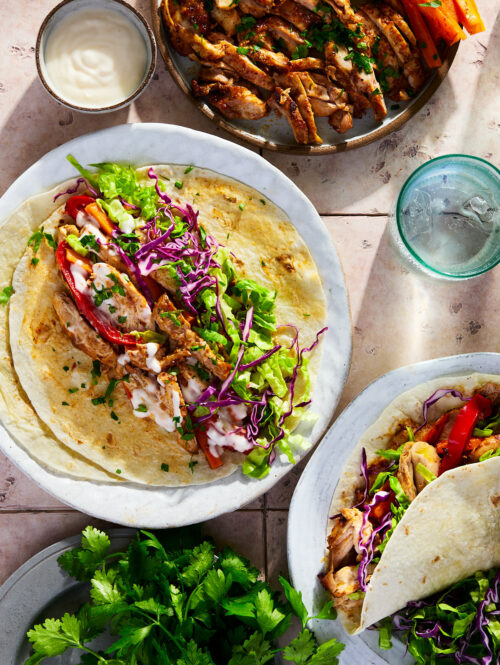 Spiced chicken, carrots, shredded lettuce, purple cabbage topped with garlic sauce on a tortilla.