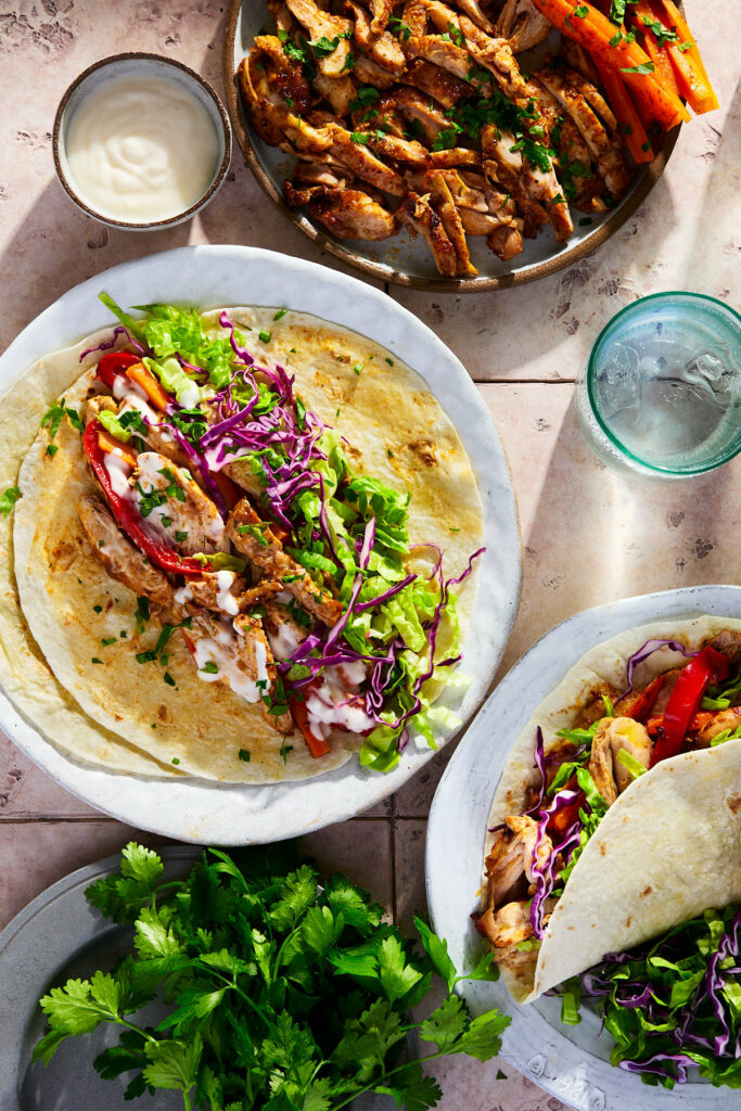 Spiced chicken, carrots, shredded lettuce, purple cabbage topped with garlic sauce on a tortilla.