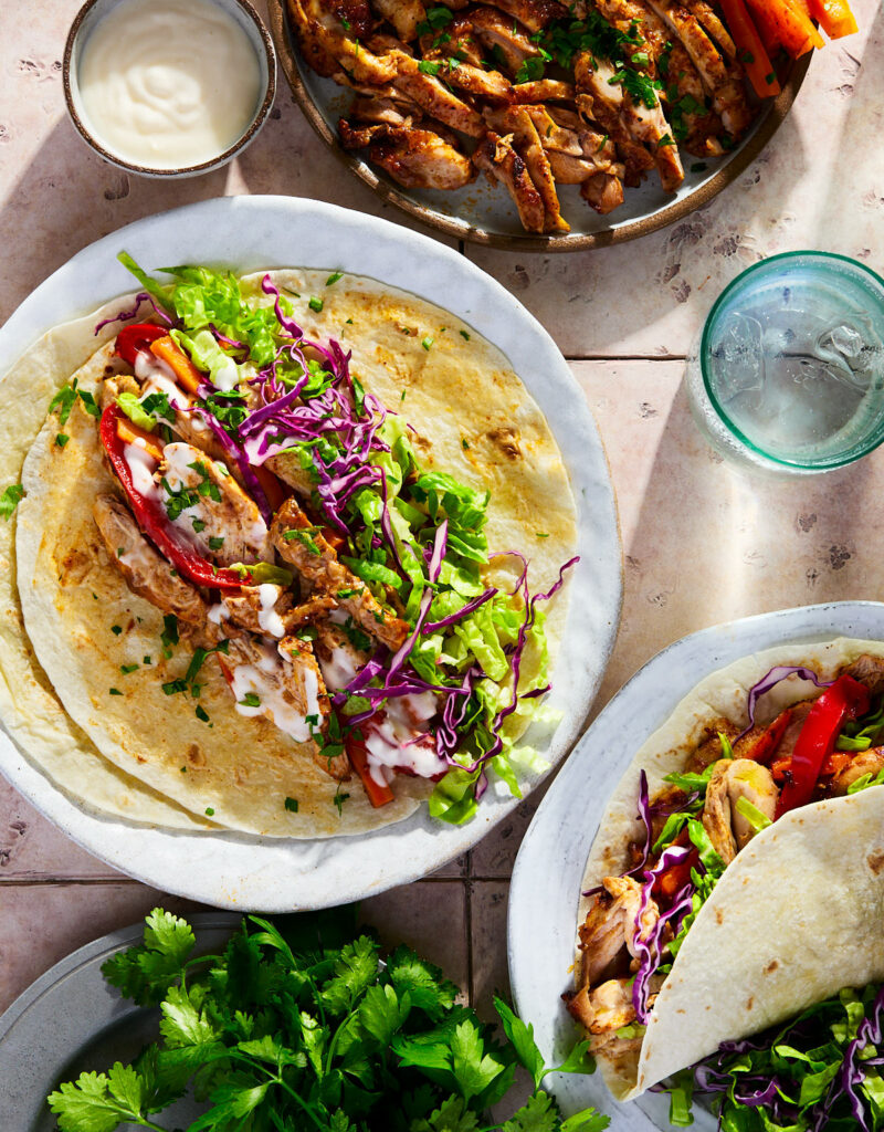 Spiced chicken, carrots, shredded lettuce, purple cabbage topped with garlic sauce on a tortilla.