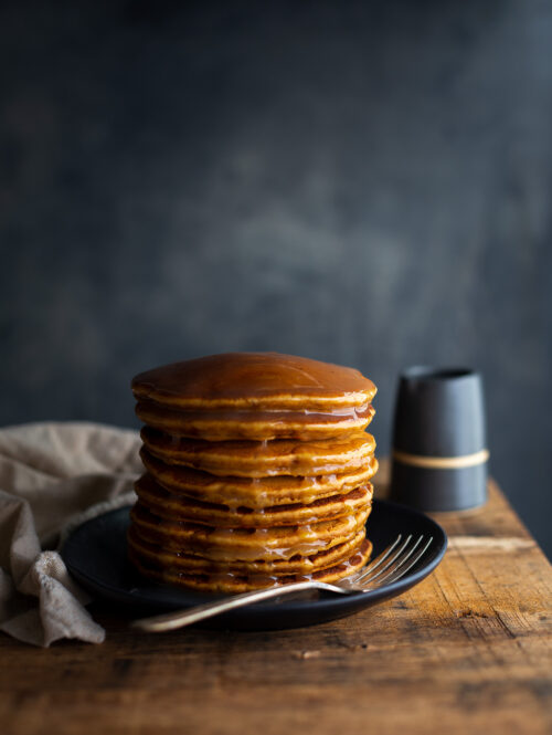 A stack of gingerbread pancakes topped with lemon sauce.