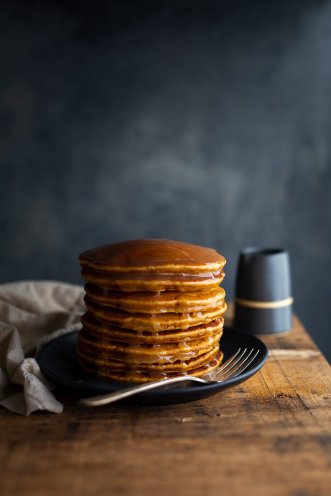 A stack of gingerbread pancakes topped with lemon sauce.