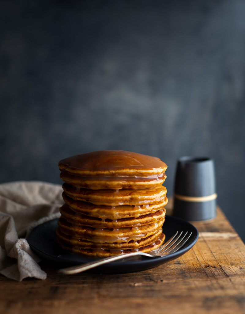 A stack of gingerbread pancakes topped with lemon sauce.