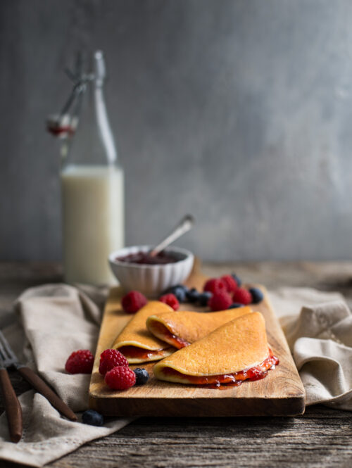 Cottage cheese pancakes on a wooden board garnished with fresh berries.
