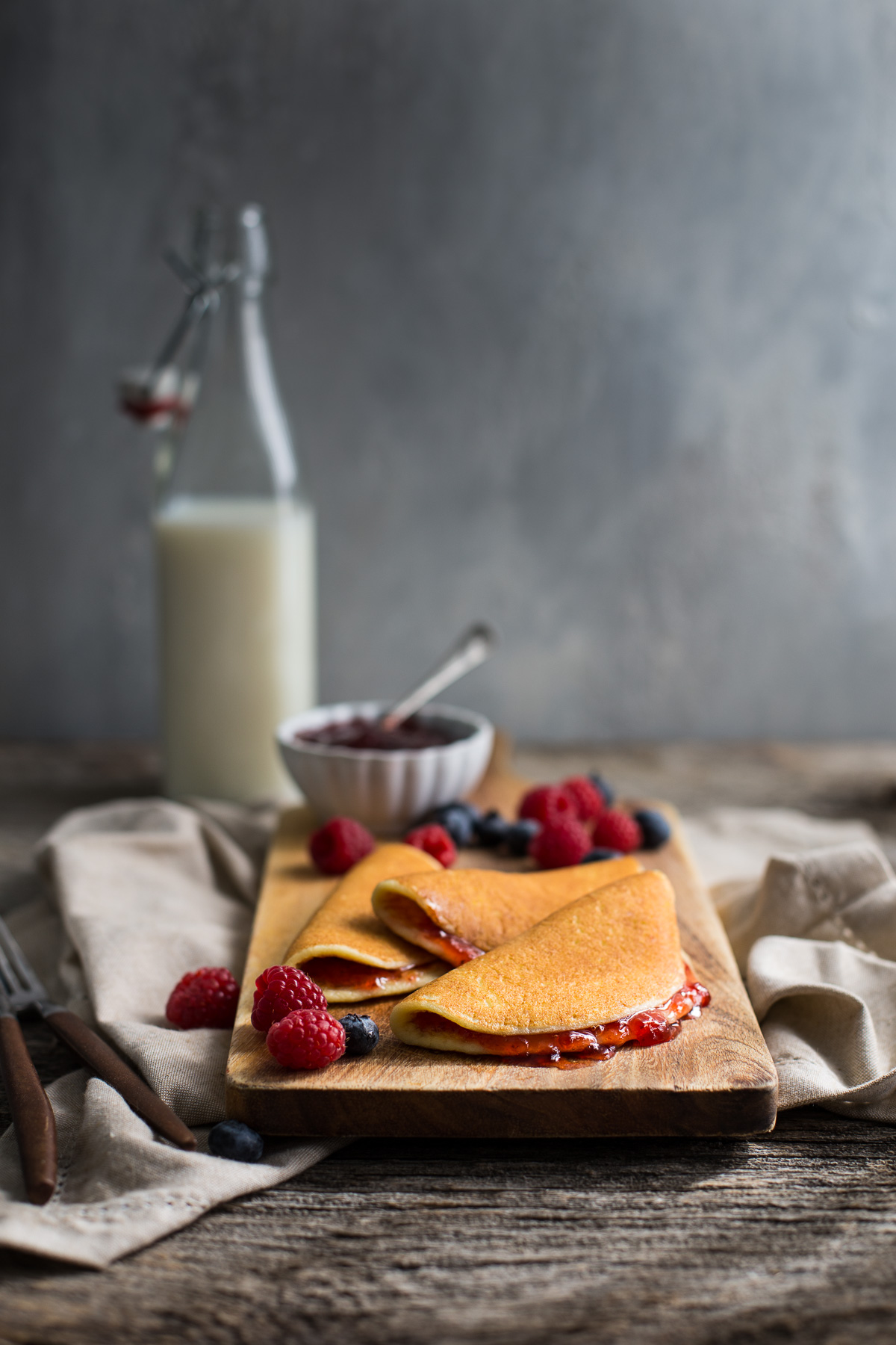 Cottage cheese pancakes on a wooden board garnished with fresh berries.