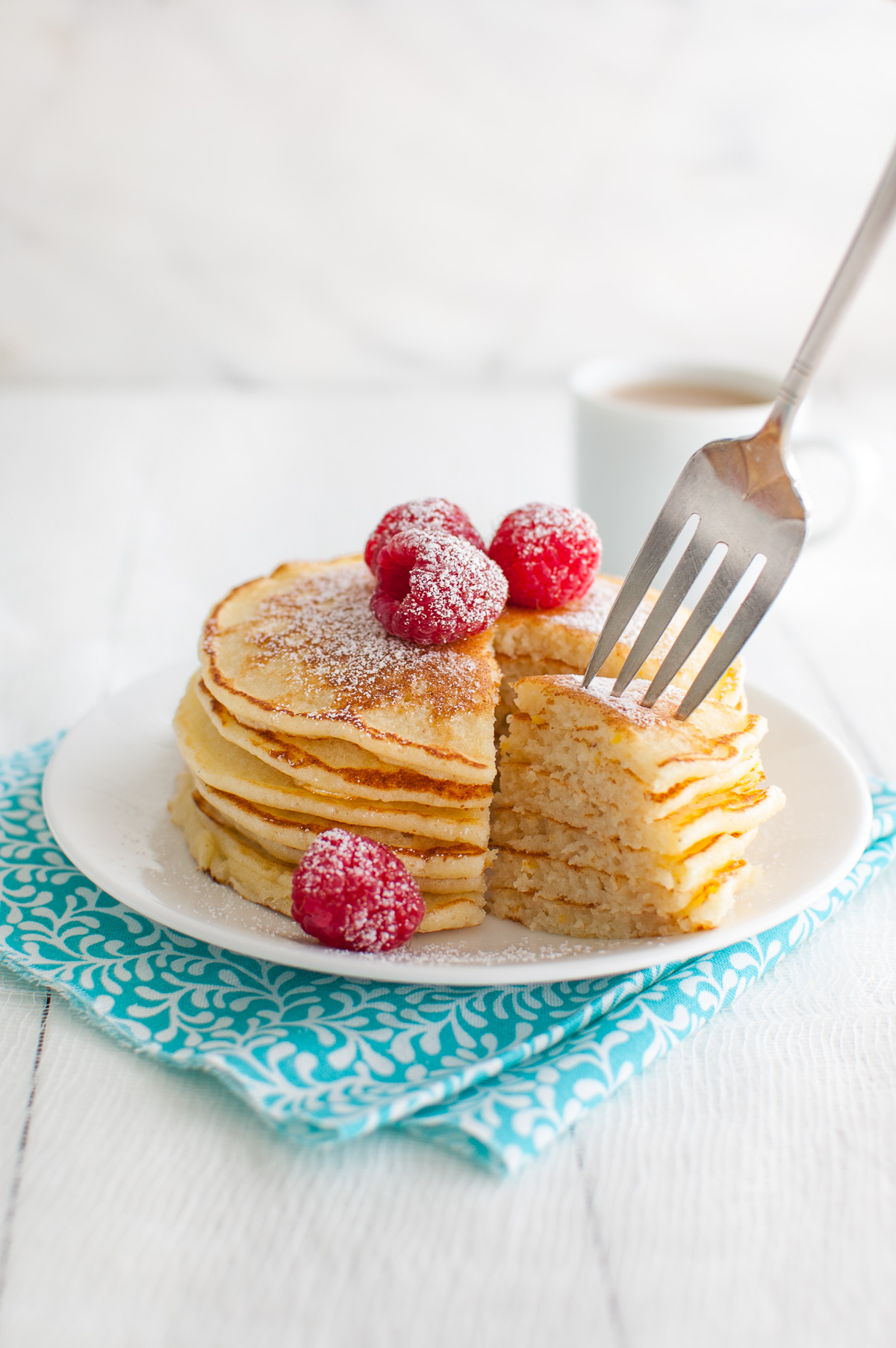 A fork picking up a cut piece from a stack of lemon soufflé pancakes.