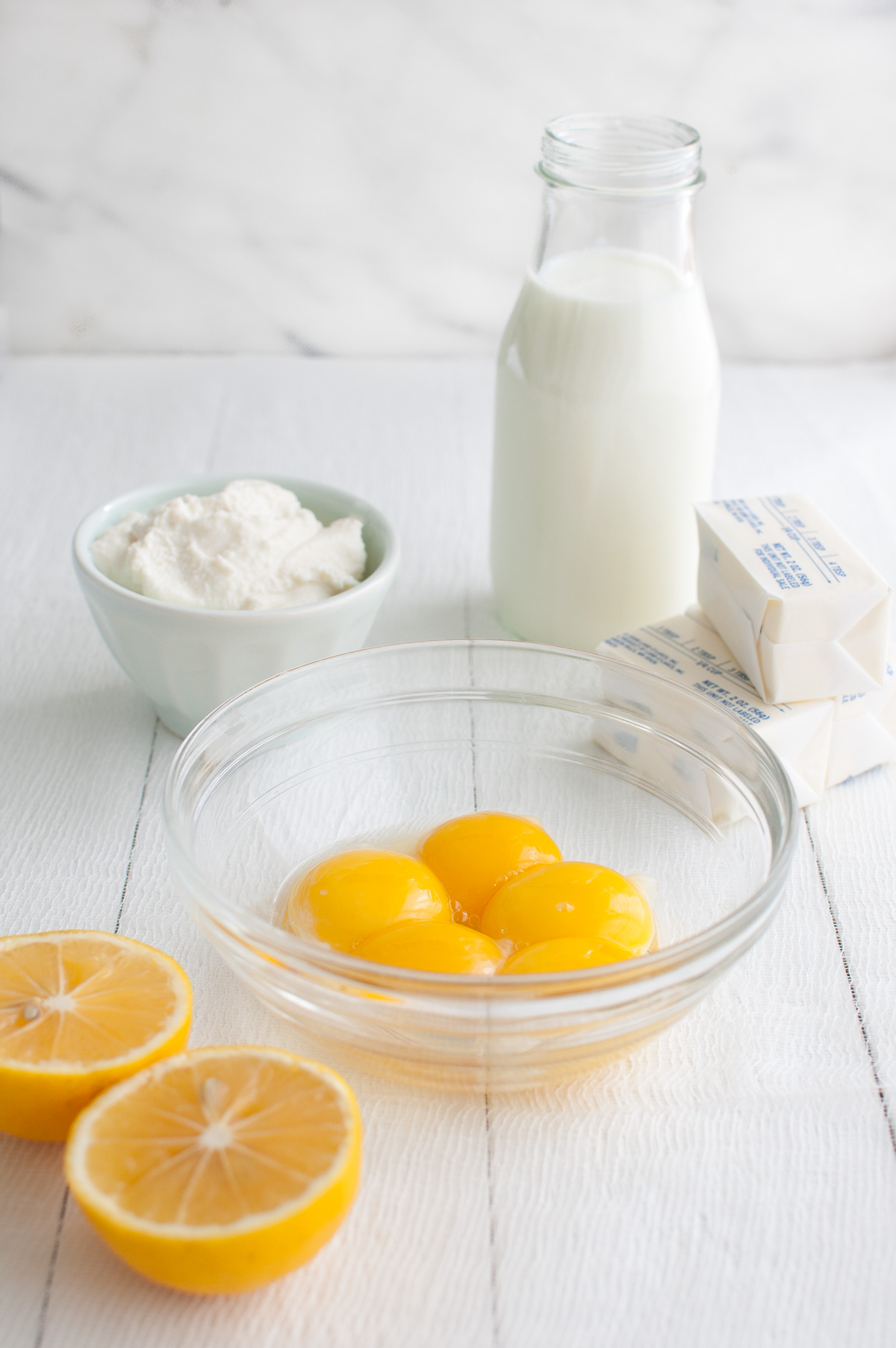 Ingredients for making lemon pancakes on a white table top.