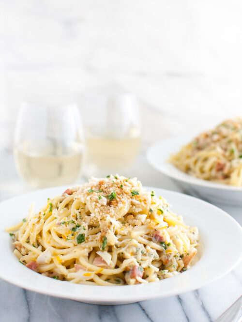 Spaghetti carbonara with crab in a white pasta bowl.