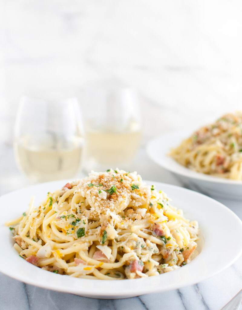 Spaghetti carbonara with crab in a white pasta bowl.