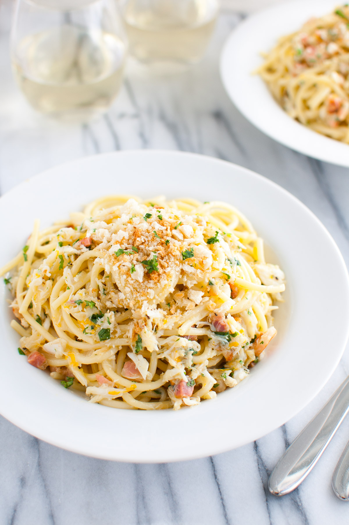 Overhead shot of spaghetti carbonara with crab in a white pasta bowl.
