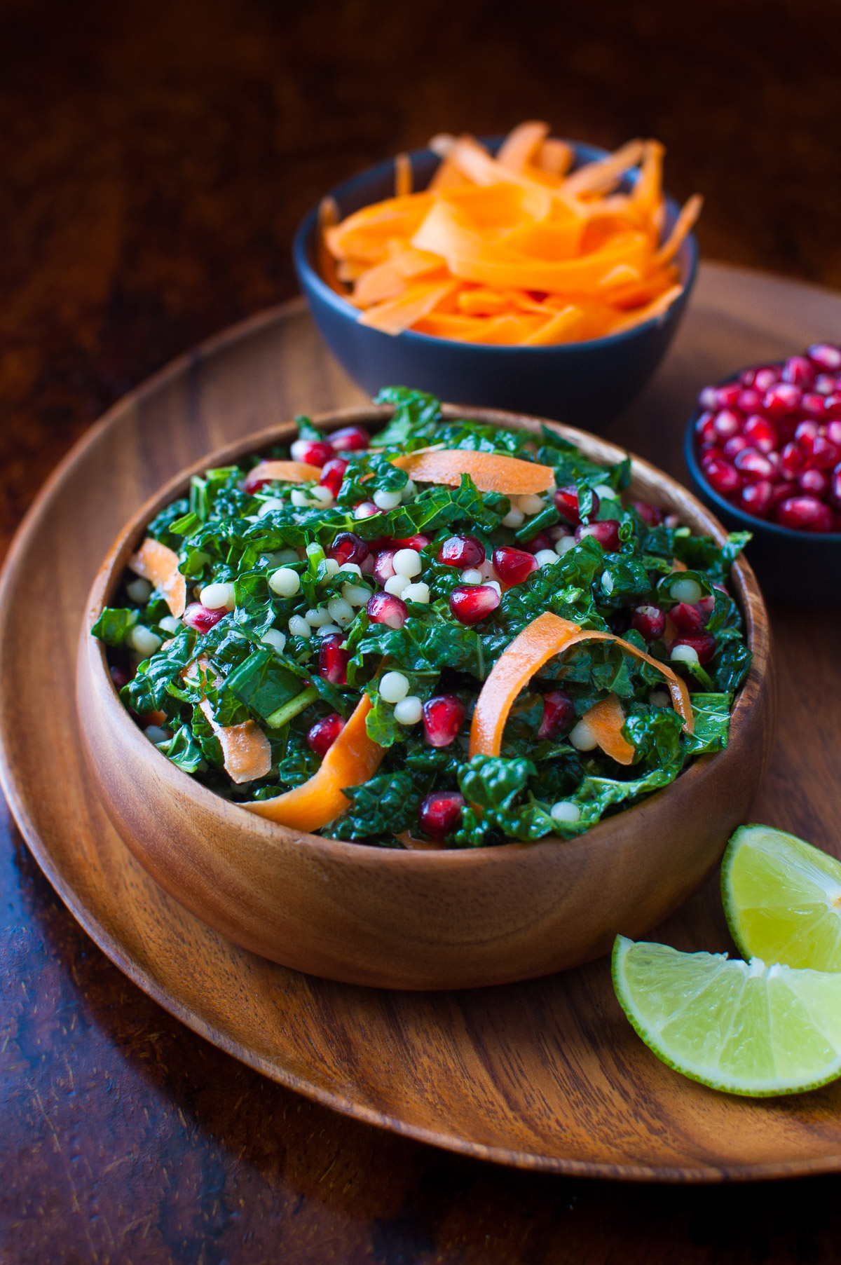 Pomegranate, Israeli couscous and kale salad in a wooden bowl.
