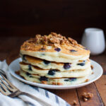 A stack of blueberry pancakes topped with some streusel.
