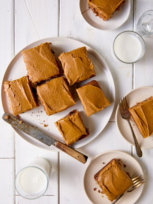 Pieces of applesauce cake frosted with penuche icing on white plates.