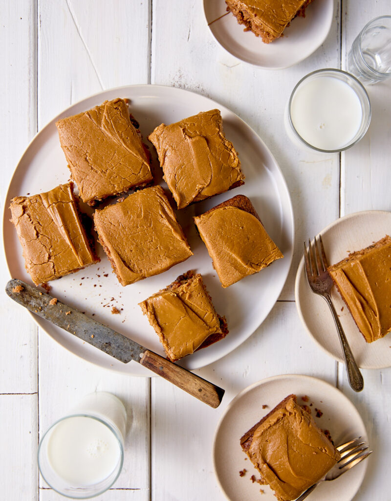 Pieces of applesauce cake frosted with penuche icing on white plates.