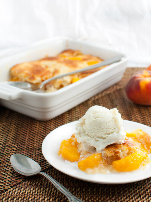 A serving of peach cobbler topped with a scoop of vanilla ice-cream.