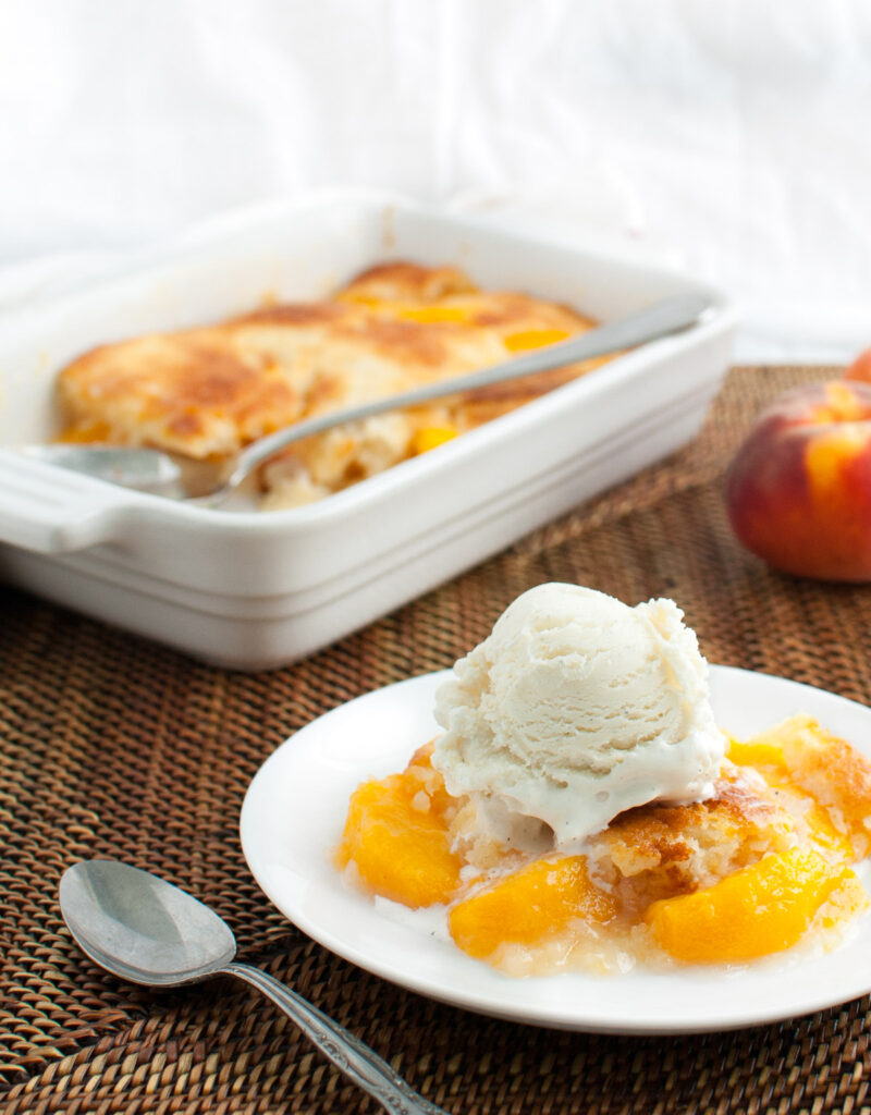 A serving of peach cobbler topped with a scoop of vanilla ice-cream.