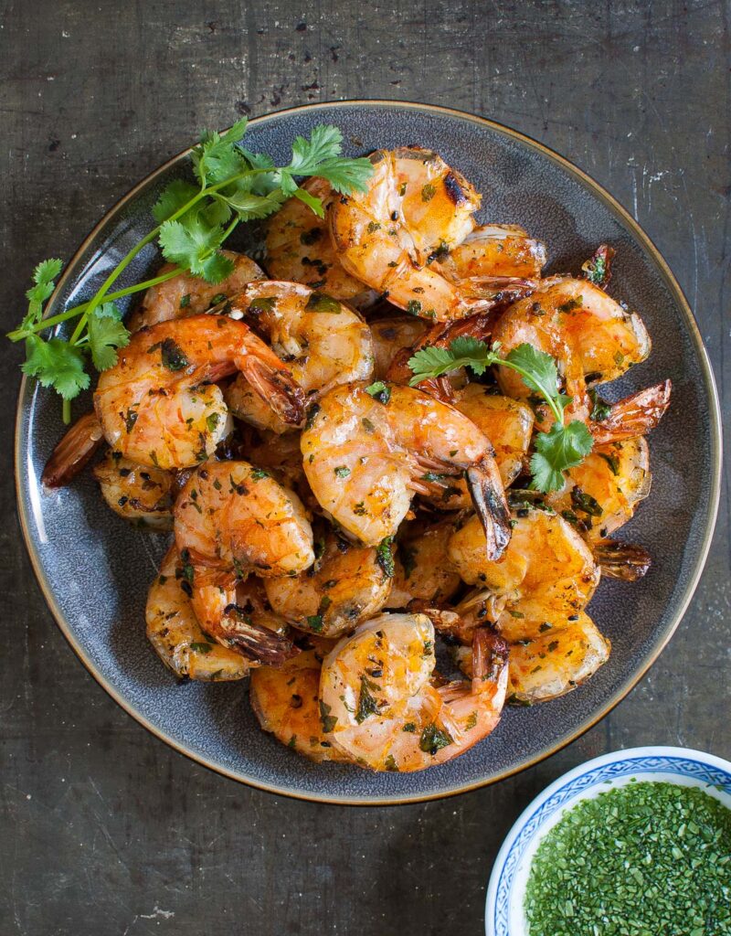 Overhead shot of some grilled shrimp on a gray plate.