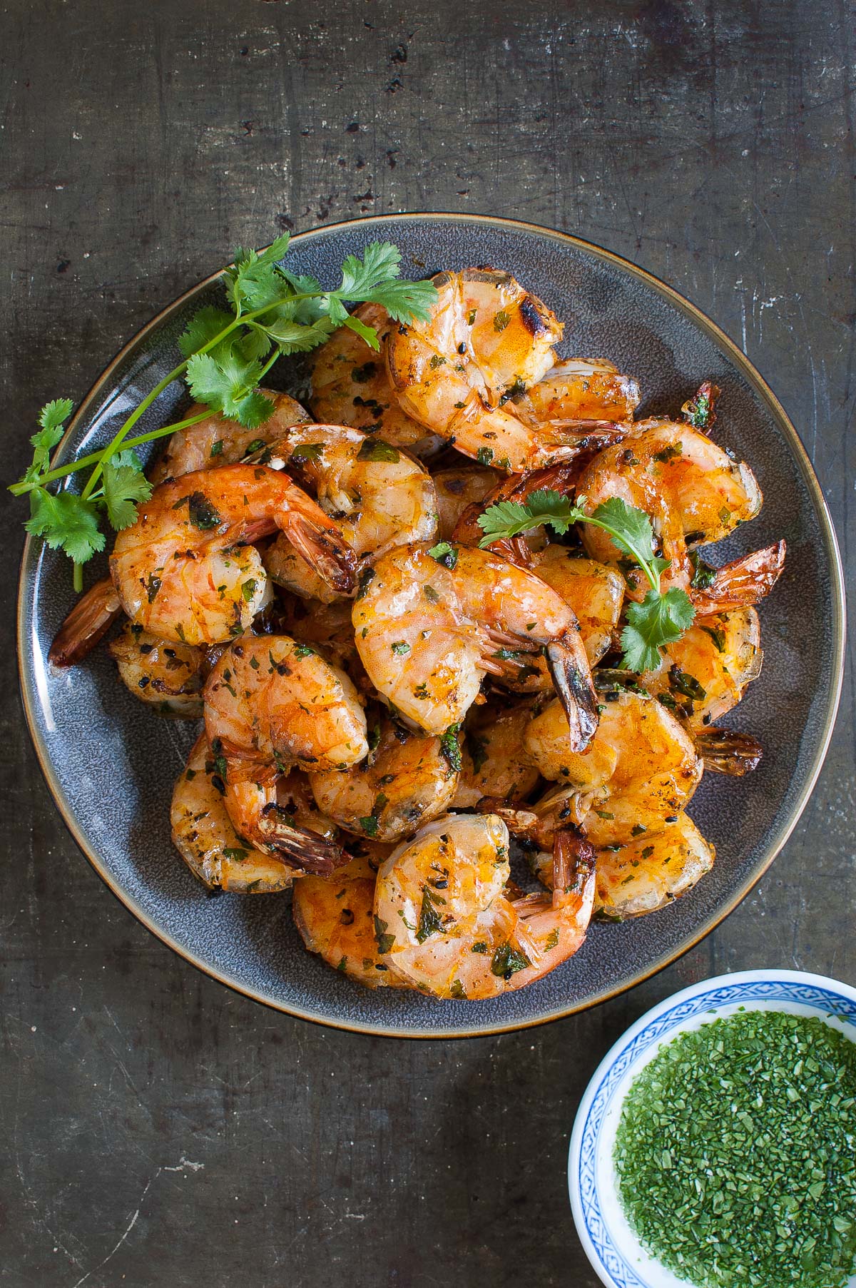 Overhead shot of some grilled shrimp on a gray plate.