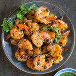Overhead shot of some grilled shrimp on a gray plate.