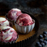 Scoops of blueberry sorbet vanilla swirl ice-cream in metal bowls on a serving tray.