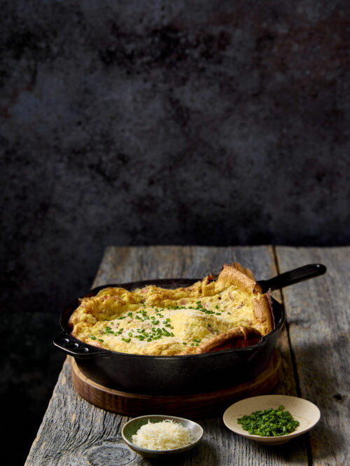 Ham and onion dutch baby on a wooden table.