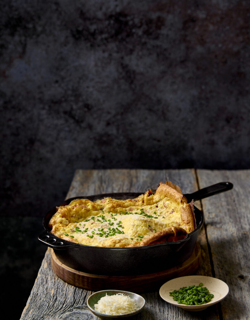 Ham and onion dutch baby on a wooden table.