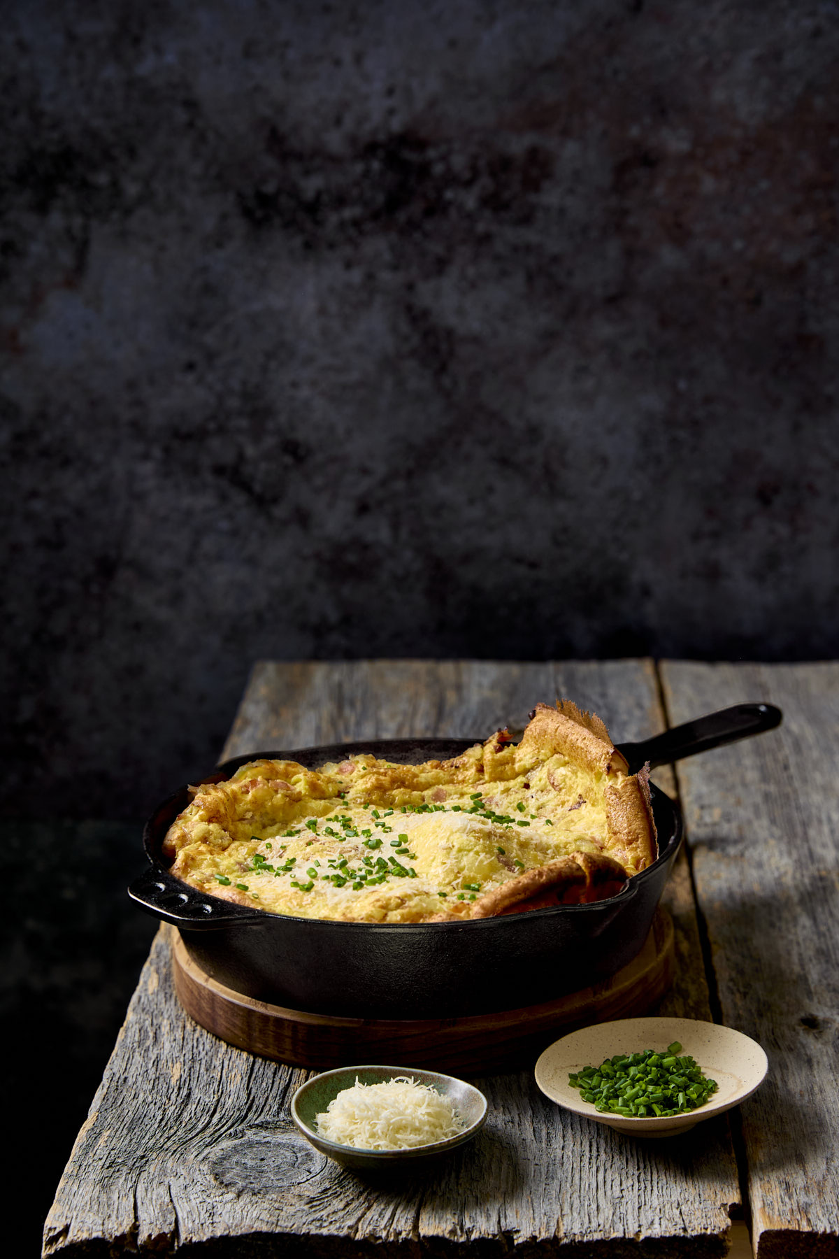 Ham and onion dutch baby on a wooden table.